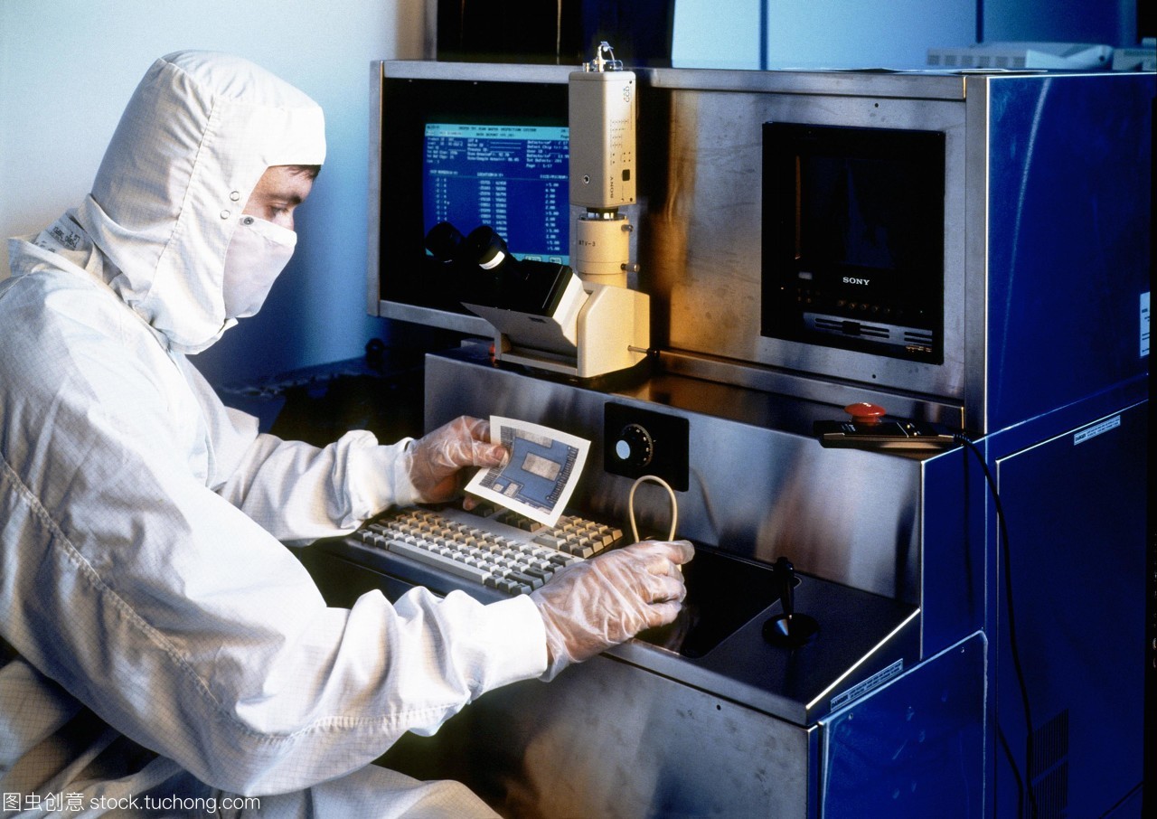 模型發(fā)布。硅晶片檢查。一名技術(shù)人員拿著一張硅片的部分照片,同時對其微電路進(jìn)行檢查。他坐在顯微鏡下觀察晶圓的放大。這是一個&ldquo;干凈的房間&rdquo;,技術(shù)人員穿著一套身衣,兜帽和面罩。在所有過程涉及人工微電路的制作和測試技術(shù)人員穿防護(hù)服和手套空氣潔凈室的過濾。即使是最小的塵埃微粒也可能破壞其中的一個微電路。